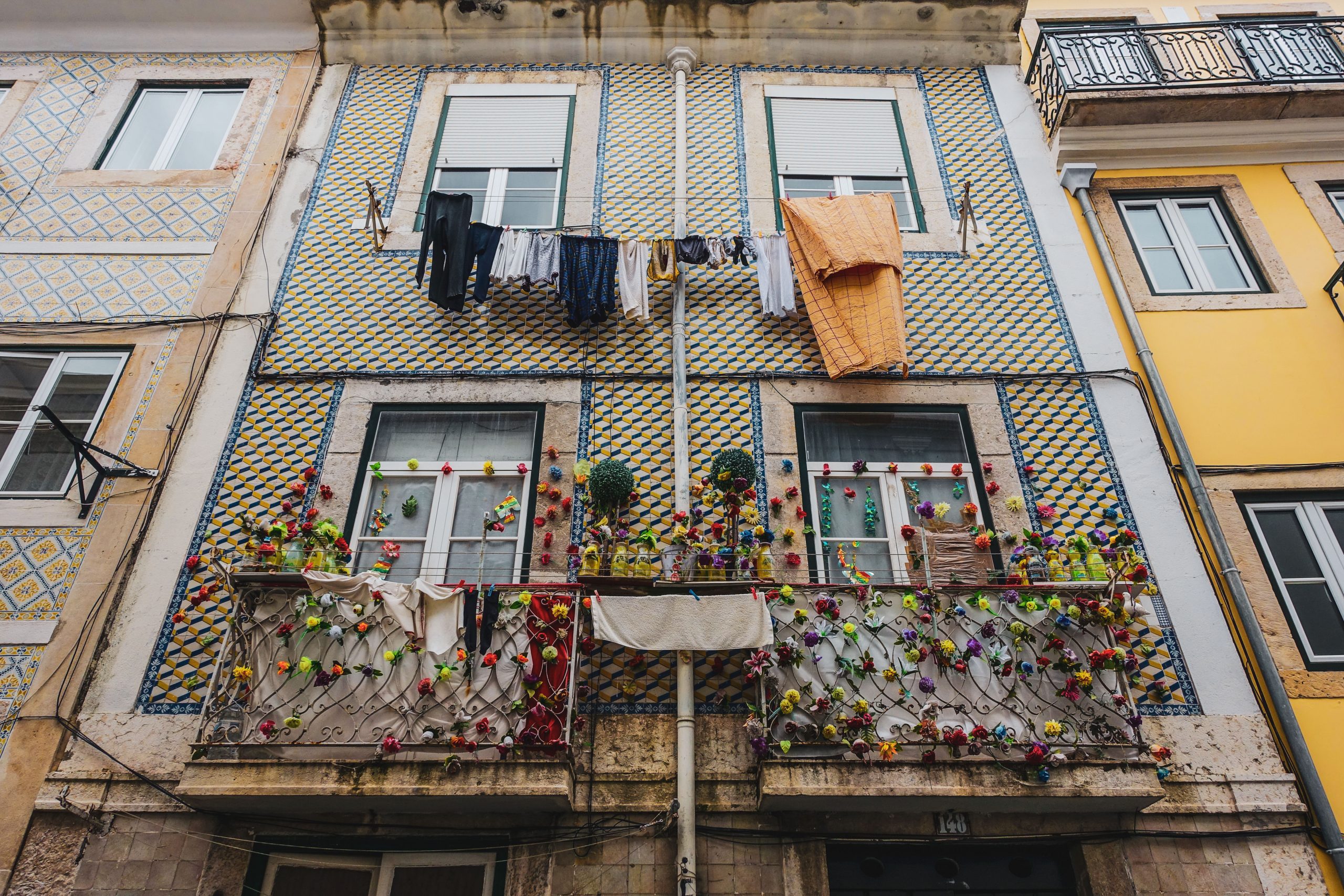 Balcon fleuri, linge séchant et azulejos