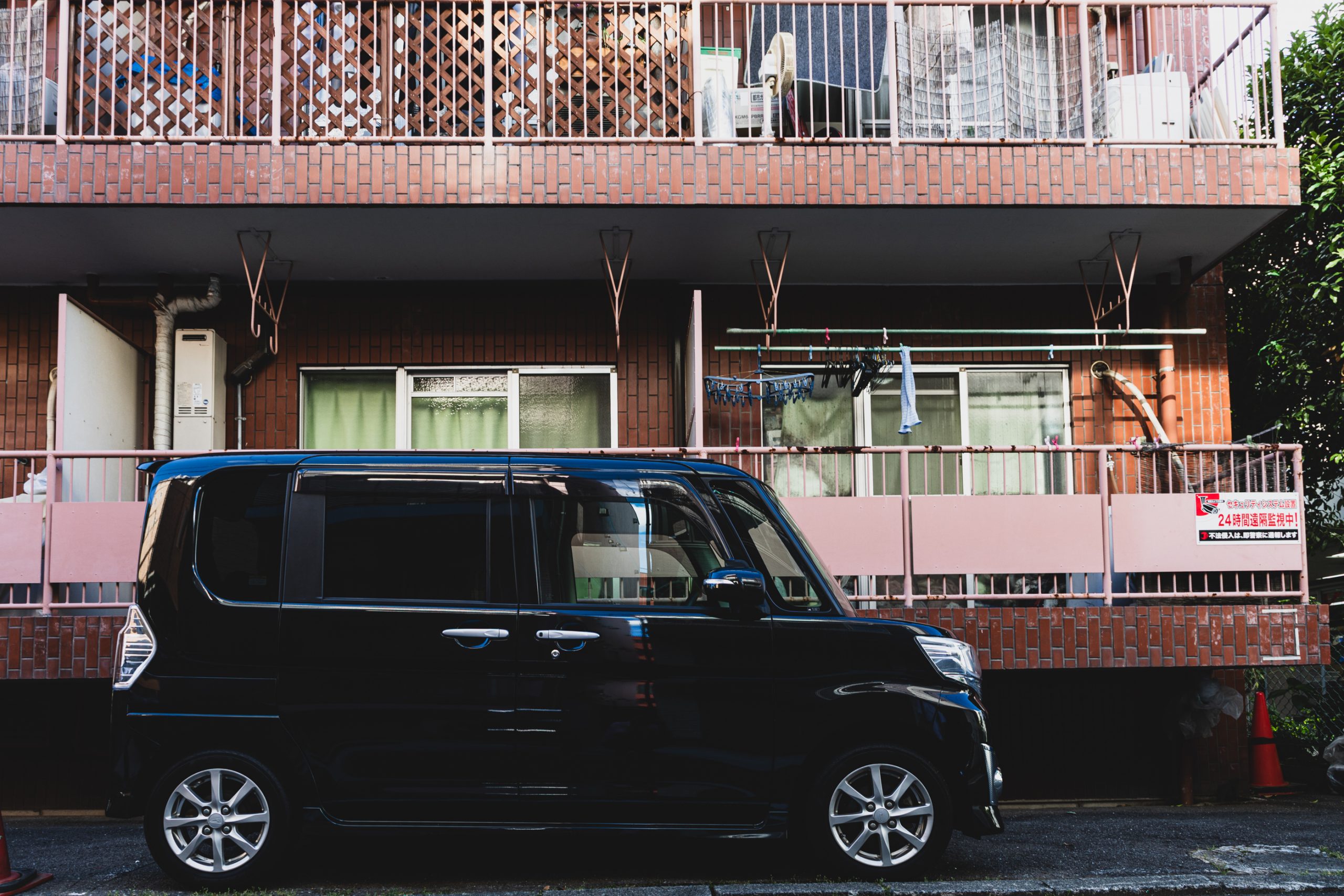 Voiture Kei noire devant immeuble résidentiel